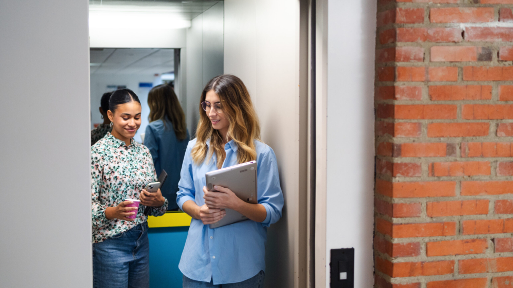 Young women discussing business inside an elevator.