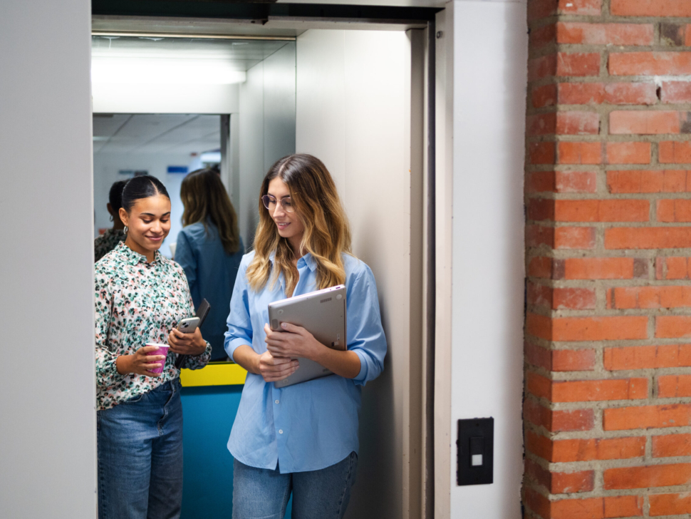 Young women discussing business inside an elevator.
